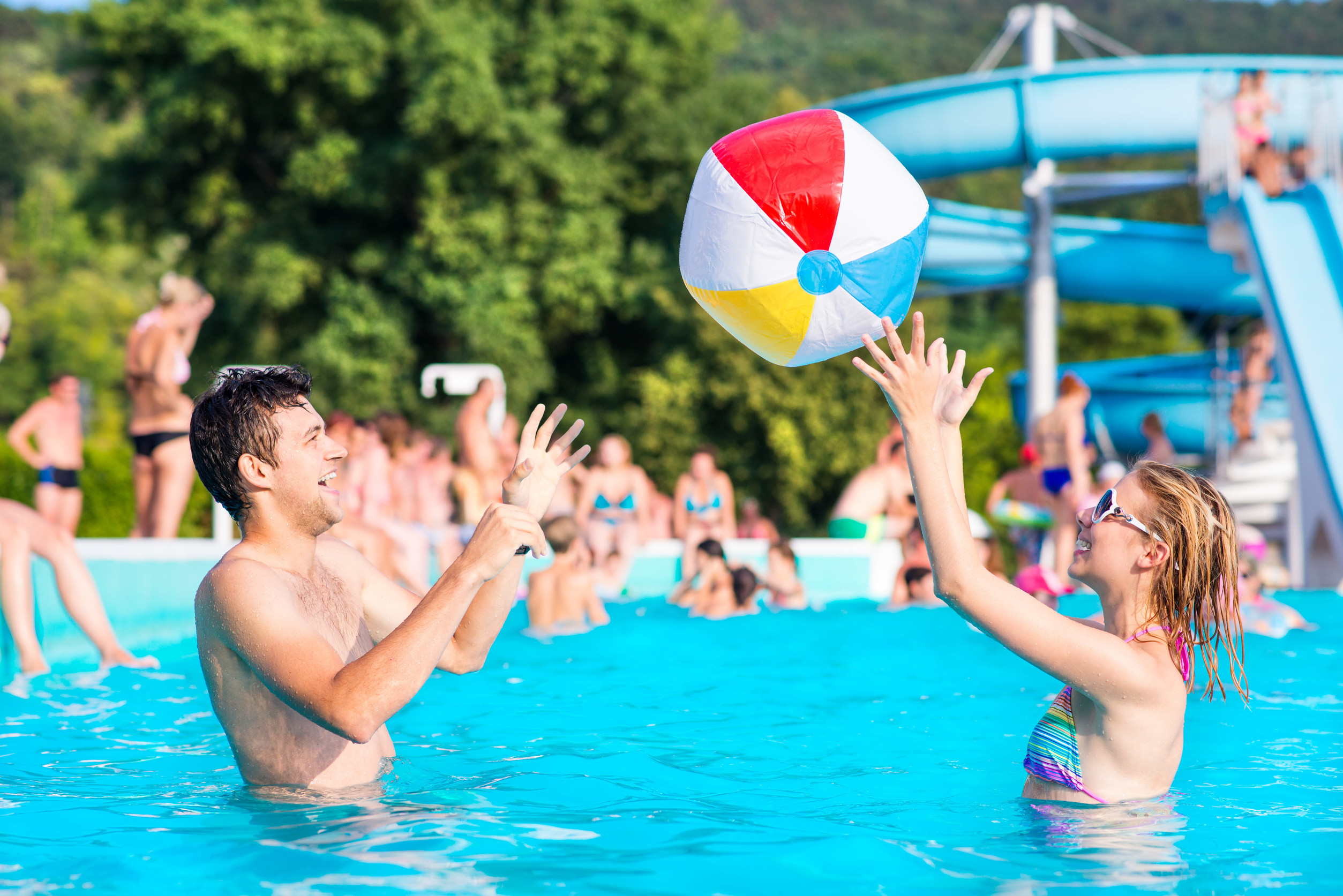 Ein junges Paar spielt mit Wasserball in einem Freibad