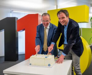 zwei Männer schneiden eine Torte an, im Hintergrund die 115_karlsruhe feiert die 115