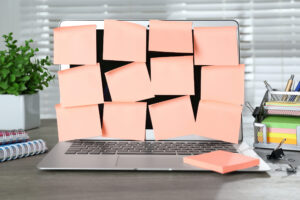 Büroschreibtisch mit einem Notebook, das mit Haftnotizen bedeckt ist