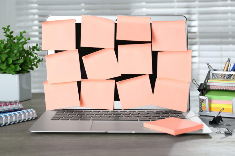 Büroschreibtisch mit einem Notebook, das mit Haftnotizen bedeckt ist