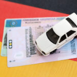 Spielzeugauto und deutscher Führerschein auf deutscher Flagge