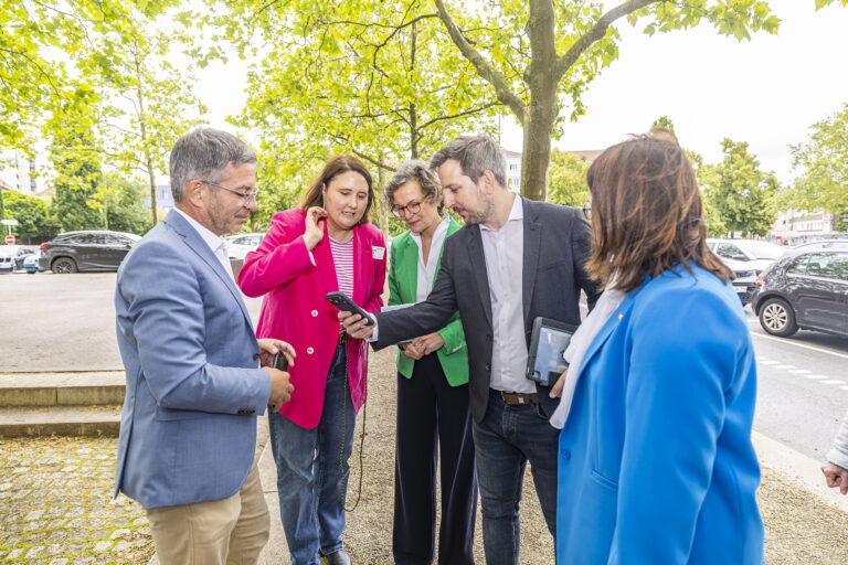 Mehrere Personen auf einem Gehweg, schauen auf ein Smartphone