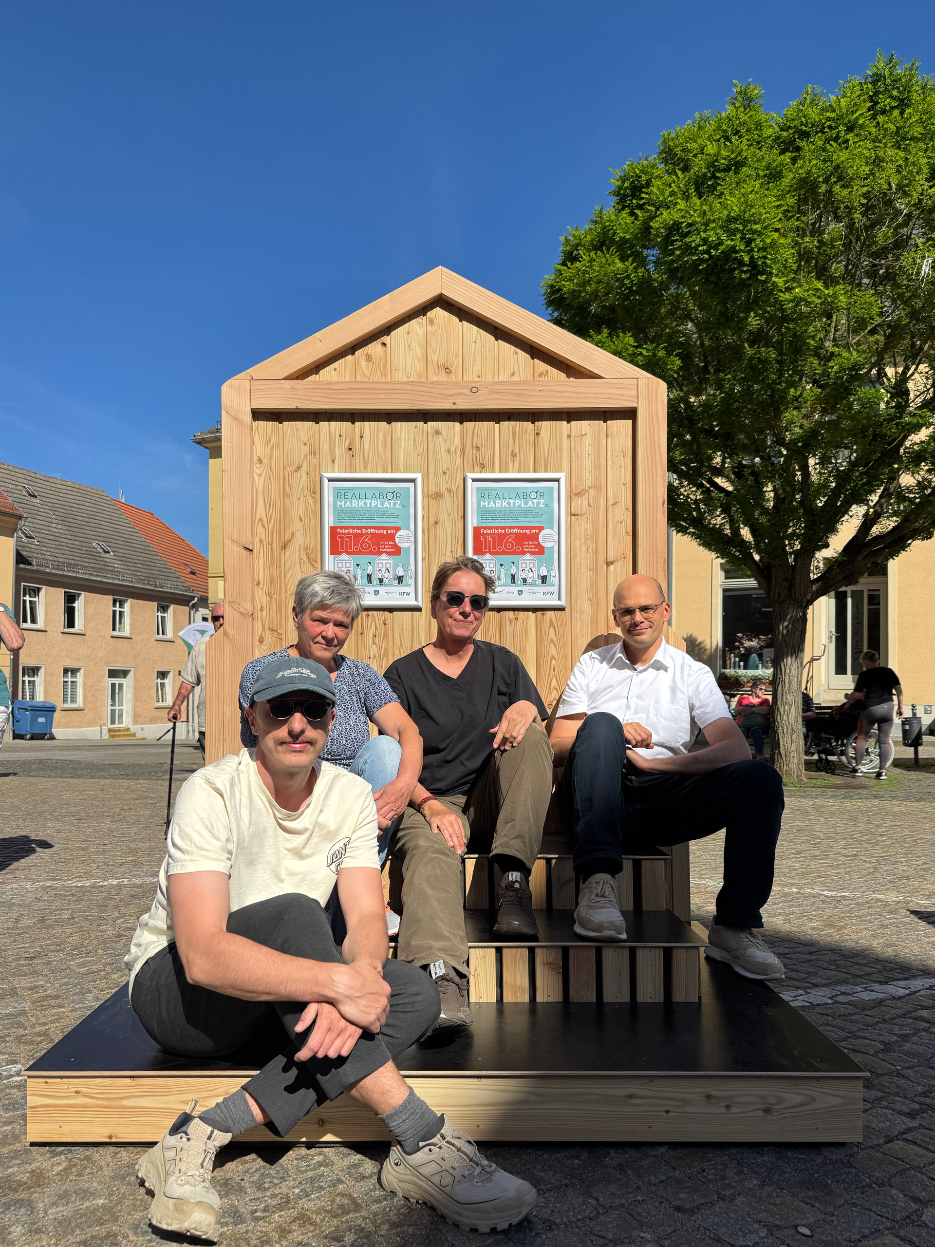 Vier Personen aus dem Bad Belziger Smart-City-Team sitzen vor einer Infotafel