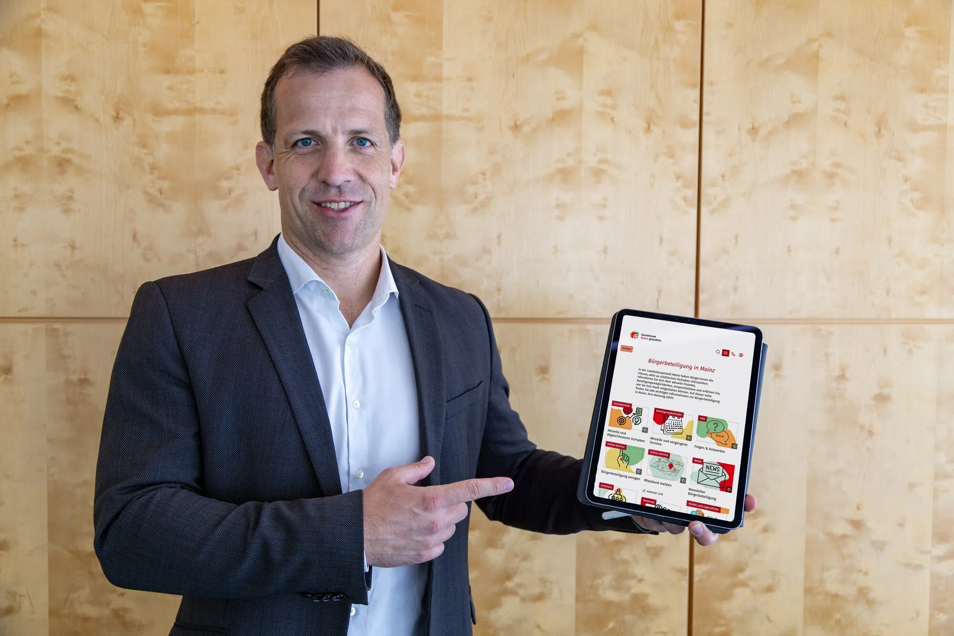 Der Mainzer Oberbürgermeister Nino Haase zeigt auf ein iPad, das die neue Microsite Bürgerbeteiligung Mainz zeigt
