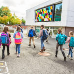 Eine Gruppe von Kindern mit Schulranzen auf dem Weg zur Schule
