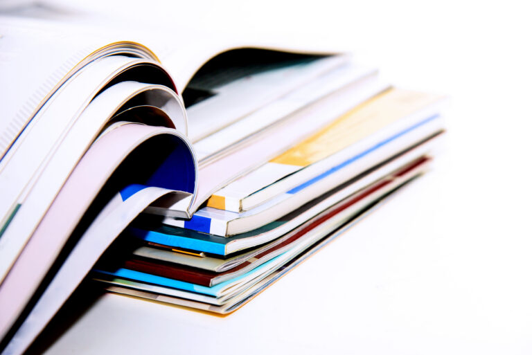 Stapel von broschierten Printprodukten, Titel nicht erkennbar, teilweise aufgeschlagen