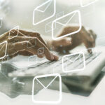 Hände tippen auf einer Tastatur, darum herum fliegen gezeichnete Briefumschläge als Symbol für E-Mail-POsteingang