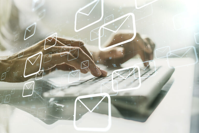 Hände tippen auf einer Tastatur, darum herum fliegen gezeichnete Briefumschläge als Symbol für E-Mail-POsteingang