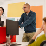 Drei Menschen mit Monitoren in einem Büro