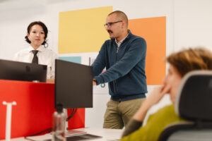 Drei Menschen mit Monitoren in einem Büro