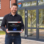 Martin Dellwing steht mit einem Laptop vor dem Haus der Vereine.