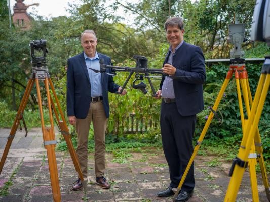 Hightech trifft Vermessungstradition: Hans Peter Jelinek (links), Leiter des Vermessungsamtes, und Erster Bürgermeister Jürgen Odszuck mit Drohne und modernen Messgeräten.