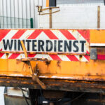 ein orangenes Winterdienstauto von hinten