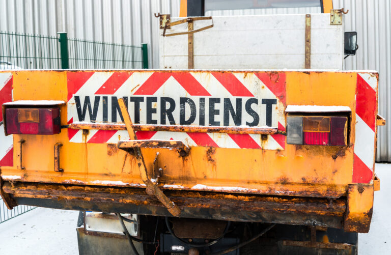 ein orangenes Winterdienstauto von hinten