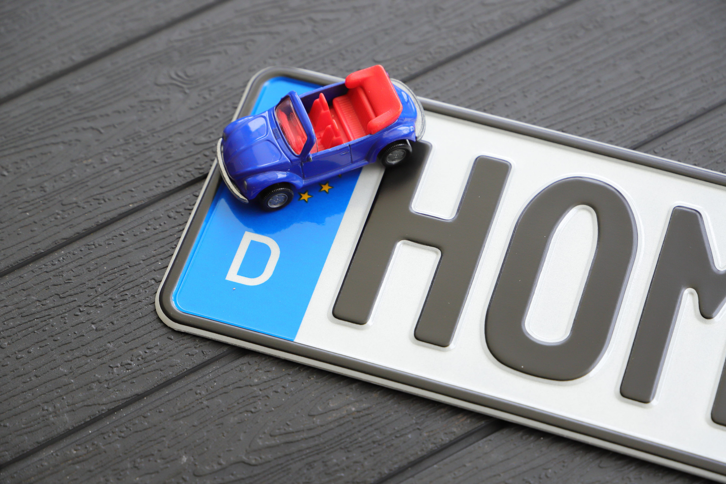 Deutsches Nummernschild plus Spielzeugauto auf einem Holztisch