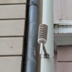 Hausfassade mit Klimasensor, dieser sieht etwa aus wie ein weiß angestrichenes Mikrofon.
