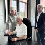 Christoph Schnaudigel, Landrat Kreis Karlsruhe sitzt vor einem Rechner, ihm schauen über Schulter ein Dezernat des LRA Karlsruhe und regisafe Geschäftsführer Frank Schellmann