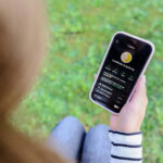 Blick über die Schulter einer Frau, die ein Smartphone hält, darauf Landkreis-Augsburg-App