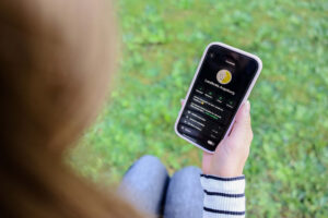 Blick über die Schulter einer Frau, die ein Smartphone hält, darauf Landkreis-Augsburg-App