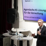 Karsten Wildberger auf einer Bühne, im Hintergrund großer Monitor mit Aufschrift "Agentic AI Hub"