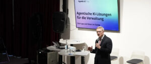 Karsten Wildberger auf einer Bühne, im Hintergrund großer Monitor mit Aufschrift "Agentic AI Hub"
