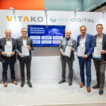 Eine Reihe von Personen an einem Messestand, auf einem Monitor steht Partnerschaft für das digitale Verkehrswesen