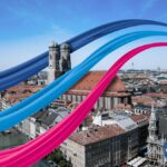 Symbolfoto Glasfaserkabel in dunkelblau, hellblau und magenta über einem Luftbild von München mit der Frauenkirche