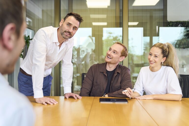 Eine Gruppe von Businesspersonen sitzen an einem Tisch und besprechen sich
