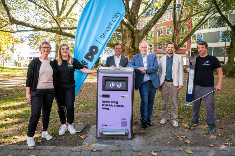 Zwei Frauen und vier Männer stehen neben einem der neuen smarten Mülleimer in Dortmund.