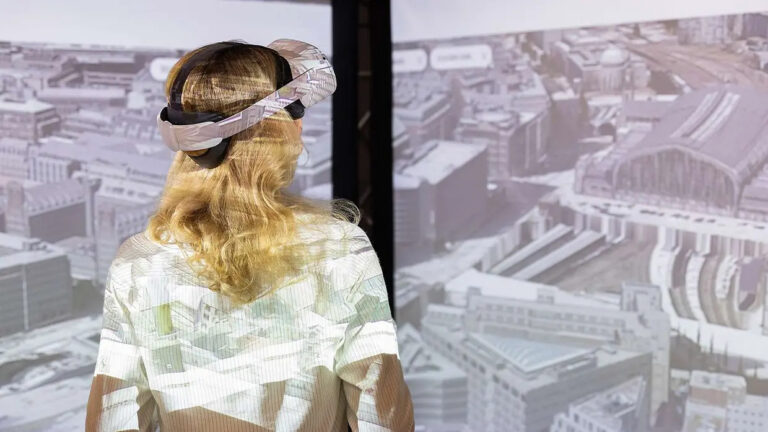 Frau mit VR-Brille schaut durch ein Panoramafenster auf eine Stadtlandschaft